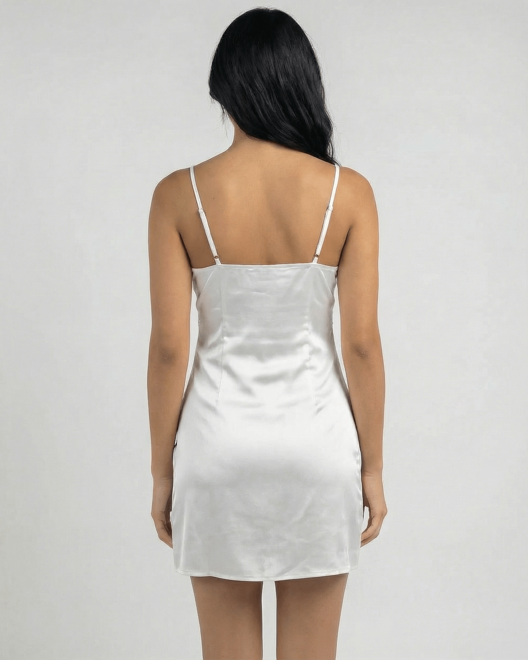 Back view of a woman wearing the Lauven Aurora Mini Dress featuring lace trim and spaghetti straps.
