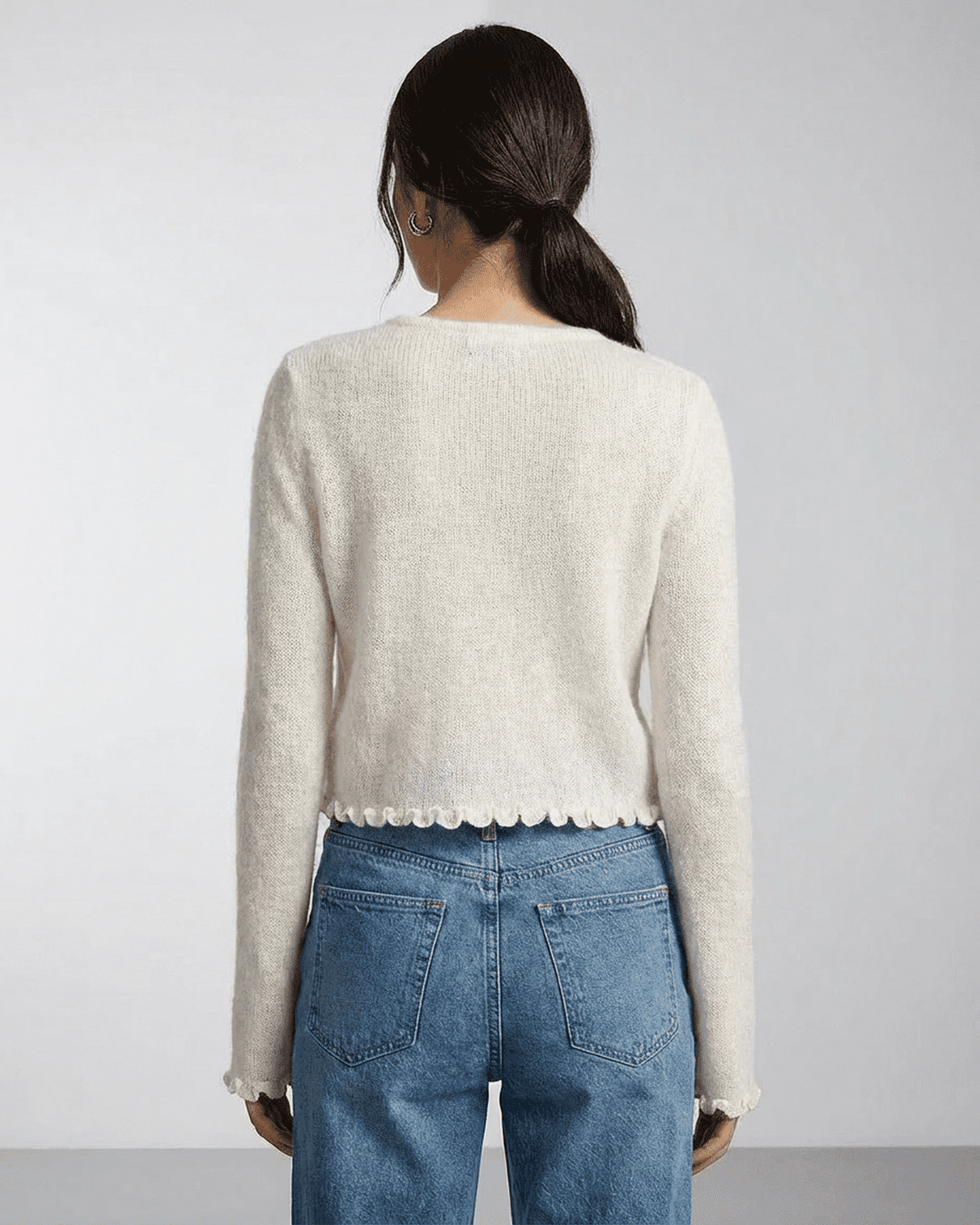 Back view of a woman in a soft knit Camellia Cardigan by Lauven, showcasing the delicate floral button detailing.