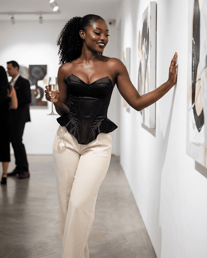 Model wearing the Celeste Corset Top by Lauven, showcasing strapless satin structure and asymmetrical finish at an art gallery.