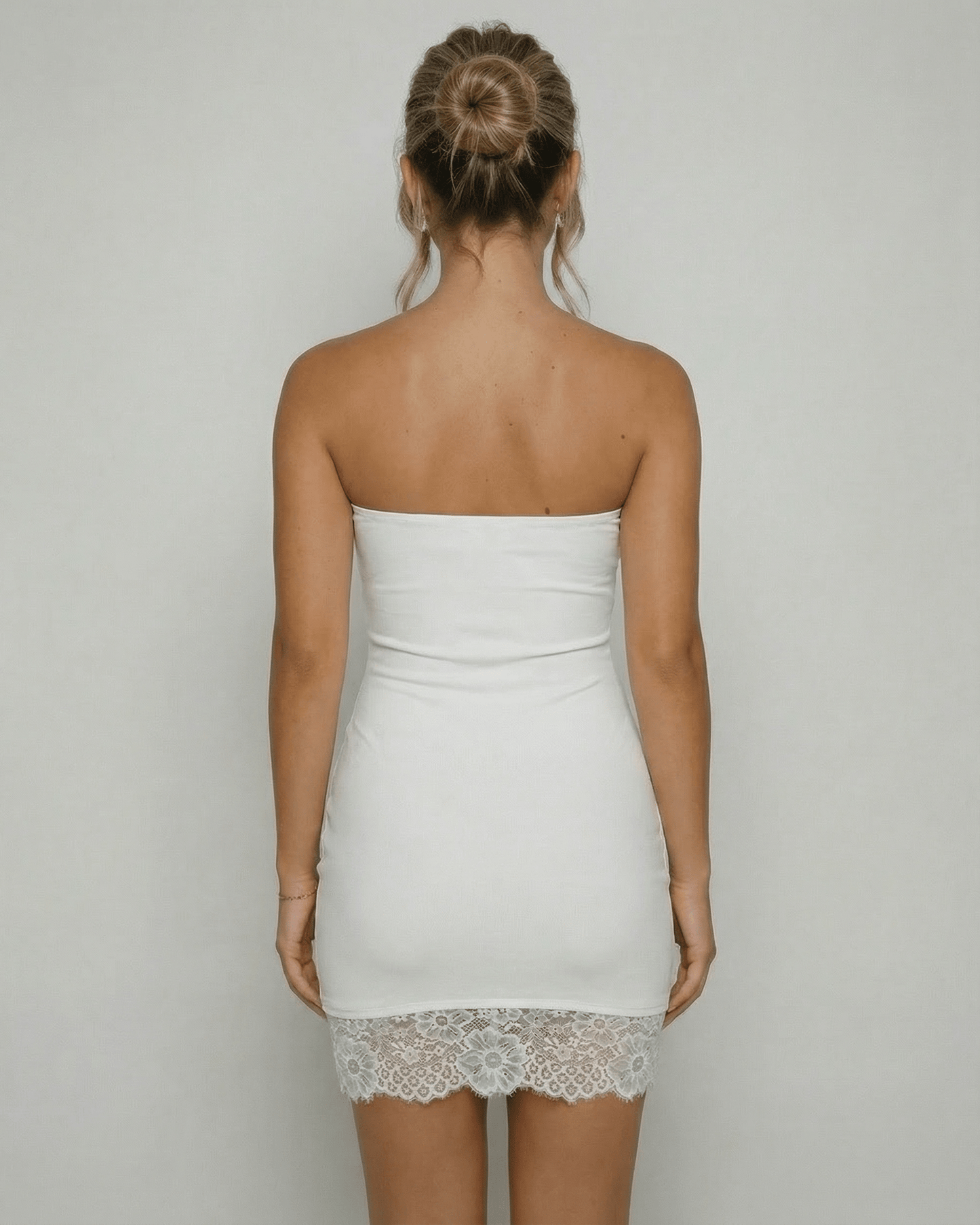 Back view of a woman wearing the Lauven Celeste Mini Dress, showcasing the strapless design and lace hem detail.