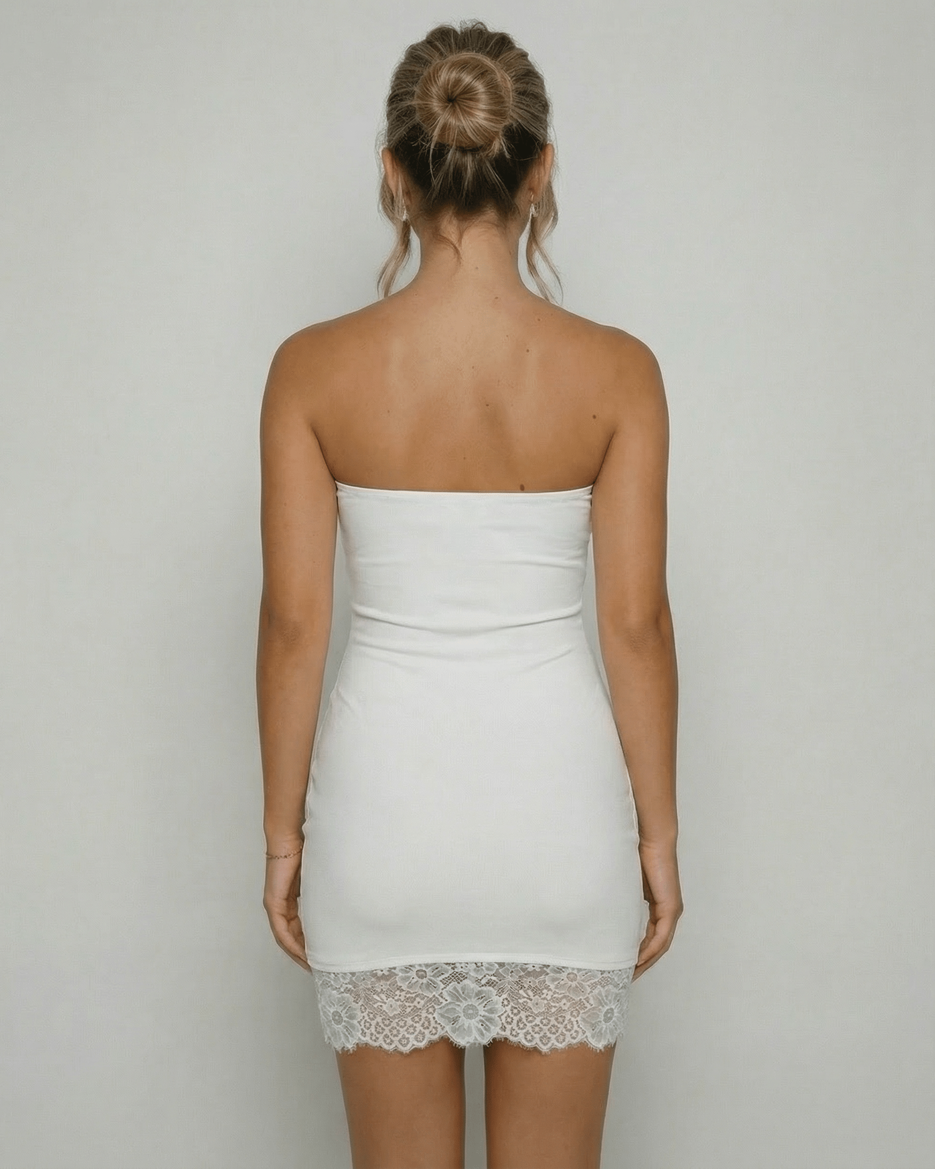 Back view of a woman wearing the Lauven Celeste Mini Dress, showcasing the strapless design and lace hem detail.