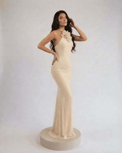 Lauven Champagne Maxi Dress featuring a halter neck and floral accent, showcasing elegant floor-length silhouette.