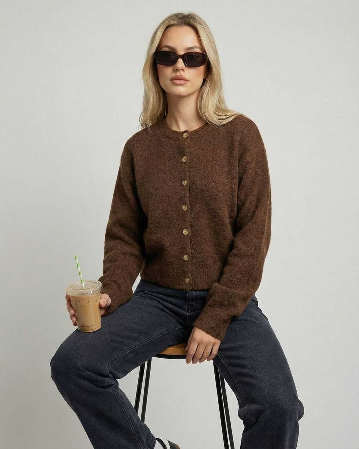 Cocoa Cardigan by Lauven, a brown button-front knit cardigan with relaxed fit worn by a model holding a drink.