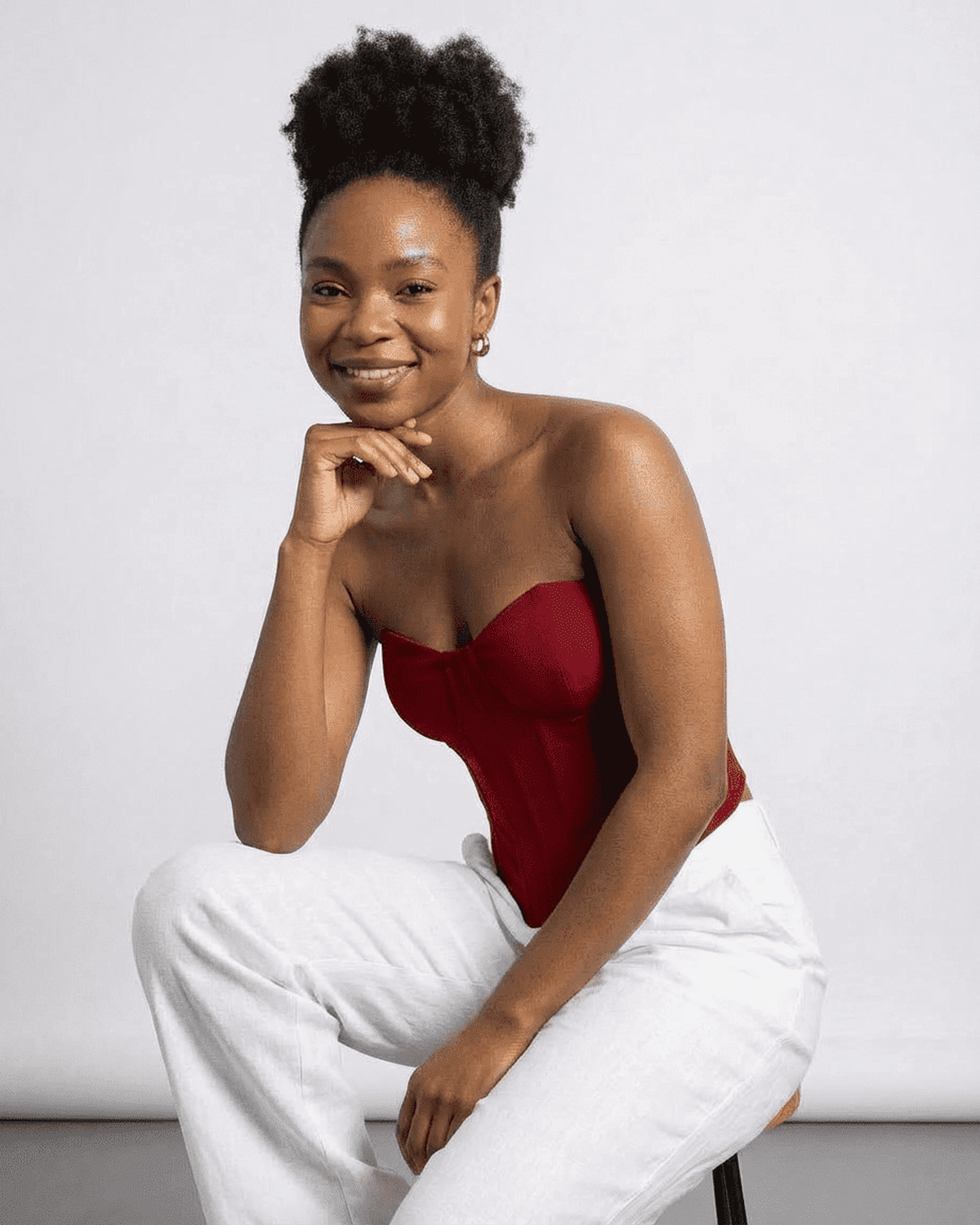 Smiling model wearing the Lauven Crimson Corset Top, a faux denim cup bustier, styled with light pants.