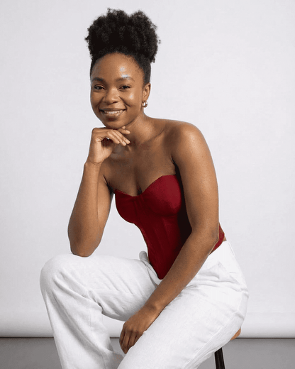 Smiling model wearing the Lauven Crimson Corset Top, a faux denim cup bustier, styled with light pants.