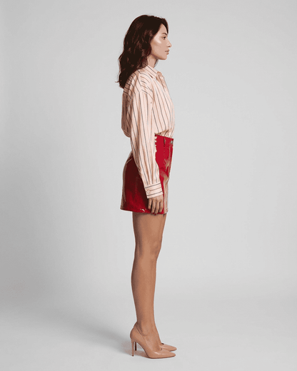 Side view of a model wearing a high-waisted Crimson Mini Skirt by Lauven, featuring a striking red glossy finish.