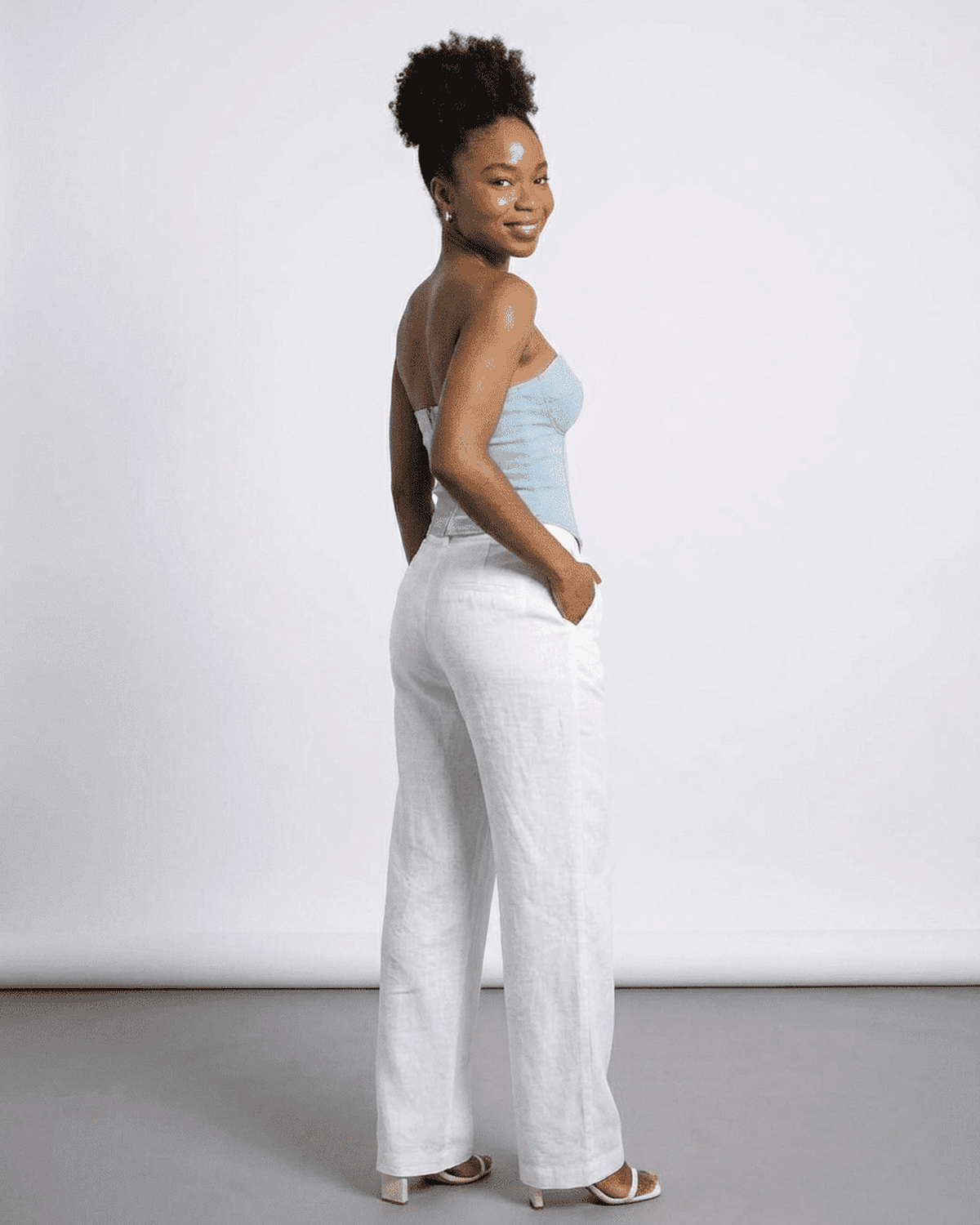 Denali Corset Top by Lauven, showcasing a woman in a faux denim bustier with stylish white linen pants.