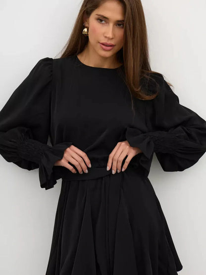 Lauven Eclipse Mini Dress in black, featuring long sleeves and a fitted waist with ruffled hem details.