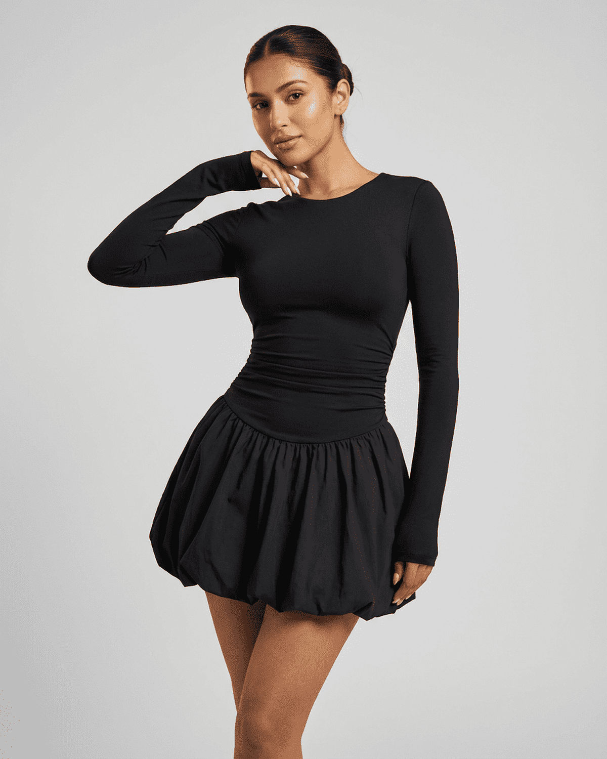 Model wearing Lauven Elara Mini Dress, a fitted stretchy elegant long sleeve tiered mini dress in black.