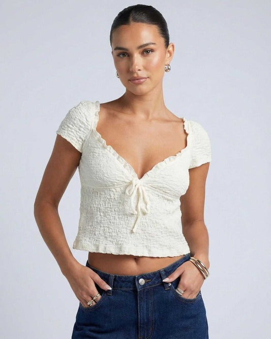 Model wearing Elara Tie Top by Lauven, a ruched V-neck crop blouse with adjustable tie detail.