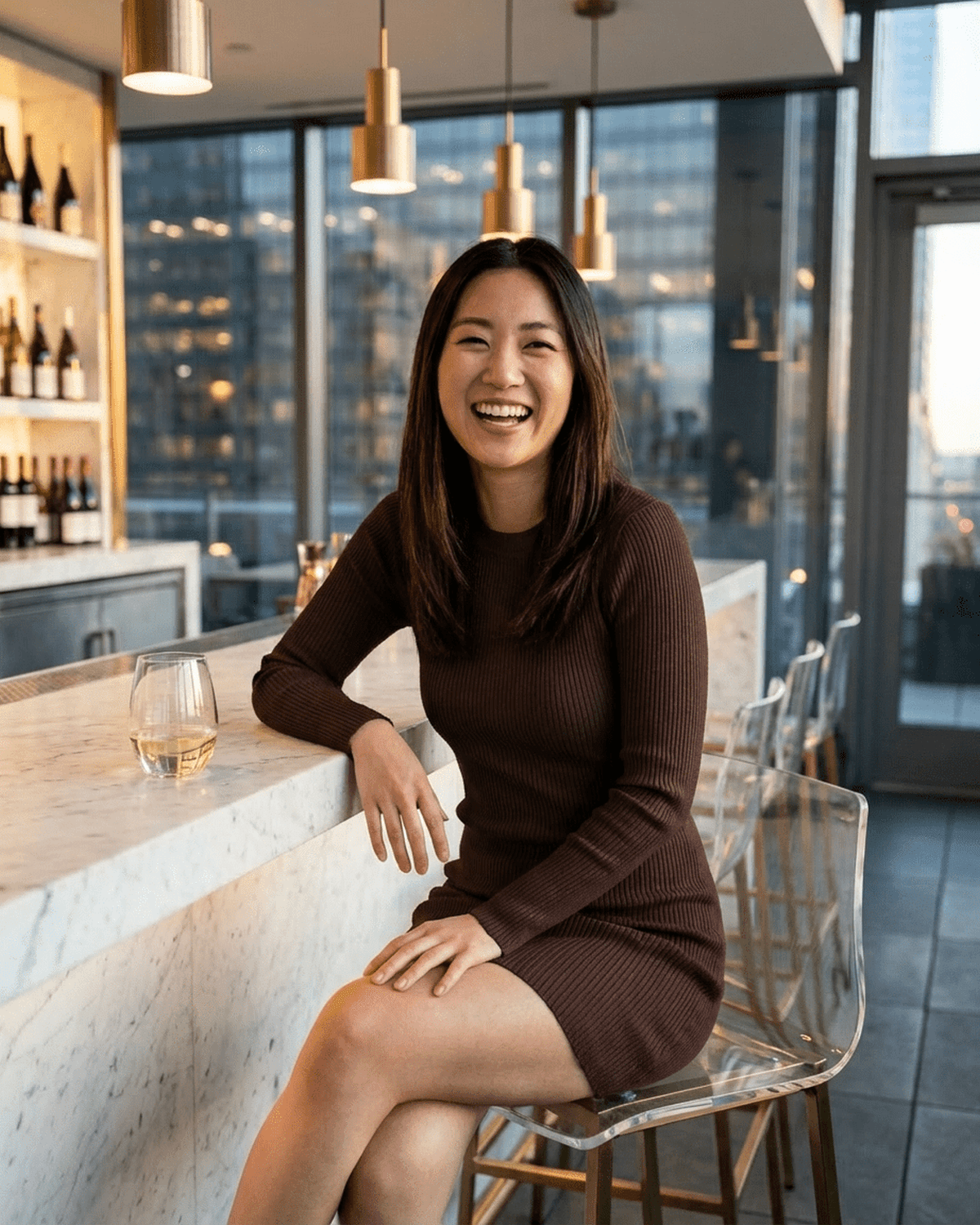 Woman smiling in a Florence Mini Dress by Lauven at a stylish bar with modern decor, enjoying a drink.