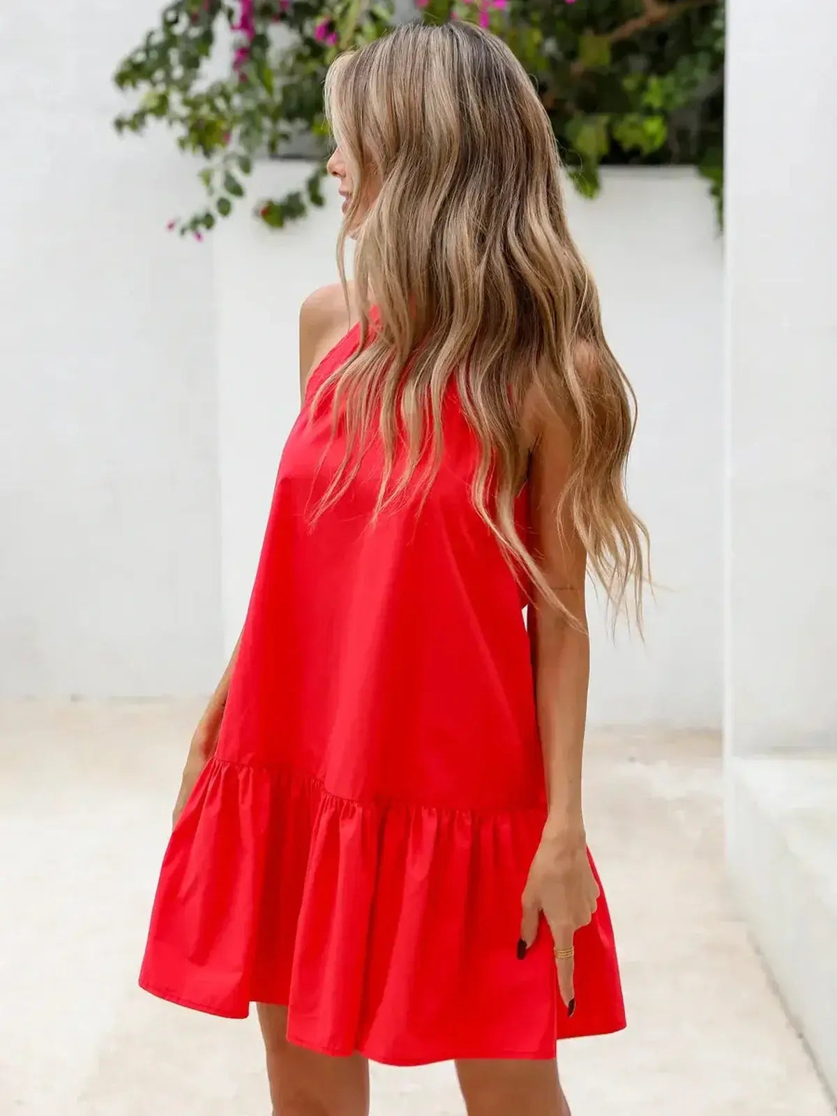 Model wearing a vibrant red flared mini dress with a halter neck and flounced hem, perfect for summer outings.