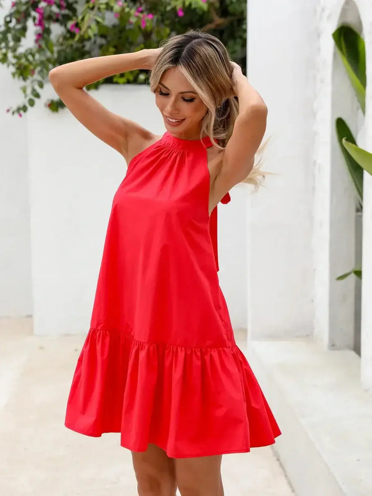 Model wearing a vibrant red halter neck mini dress with a flounced hem, perfect for summer outings.