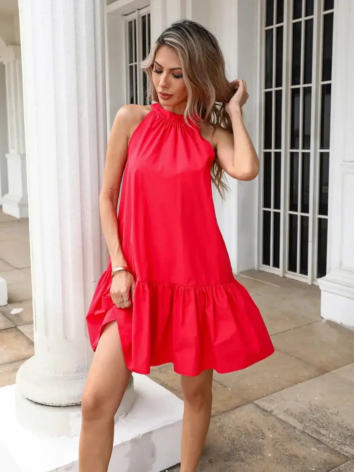 Model wearing a vibrant fuchsia flare mini dress with halter neck and flounced hem, perfect for summer outings.