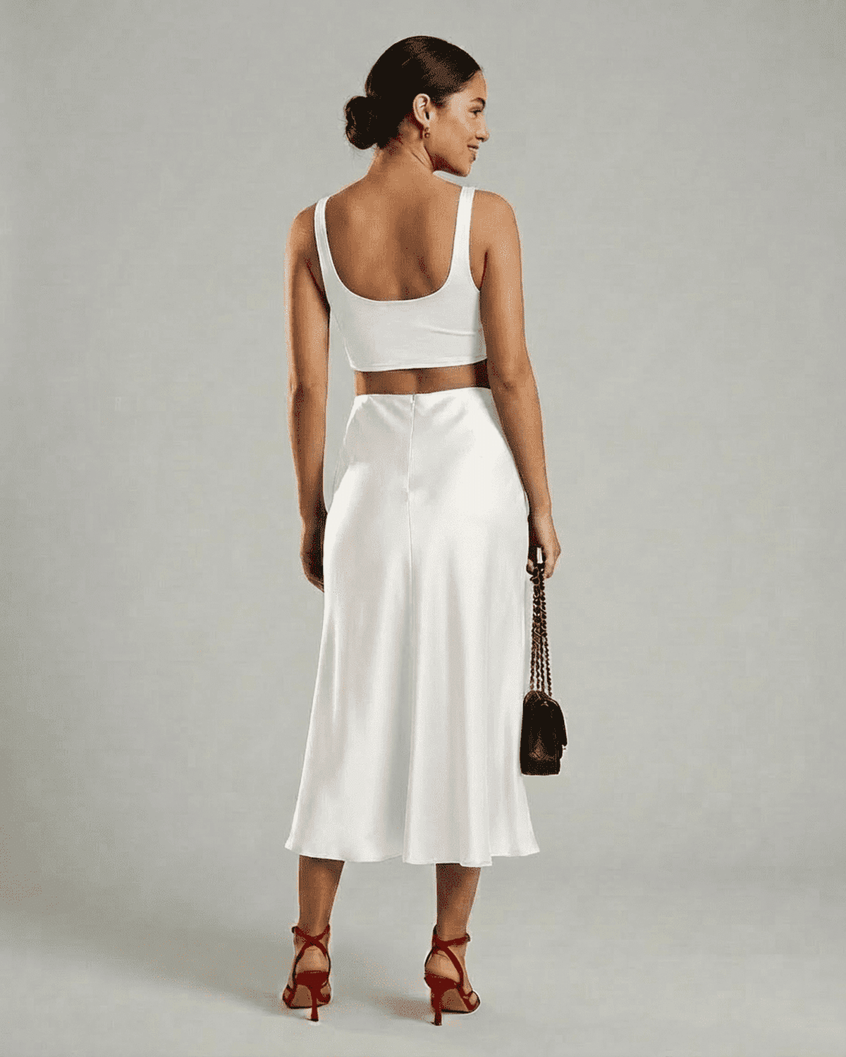 Woman in white back view wearing Lauven Luna Midi Skirt and cropped top, showcasing elegant satin mermaid design.