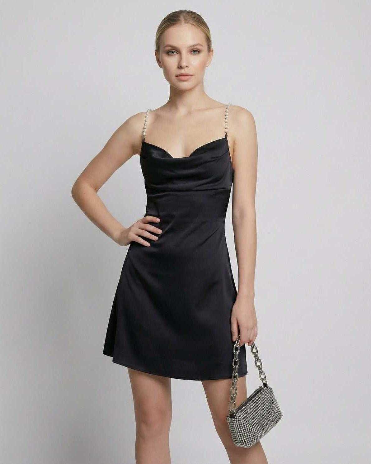 Elegant woman in Lauven Lyra Mini Dress featuring satin sheath design and pearl straps.