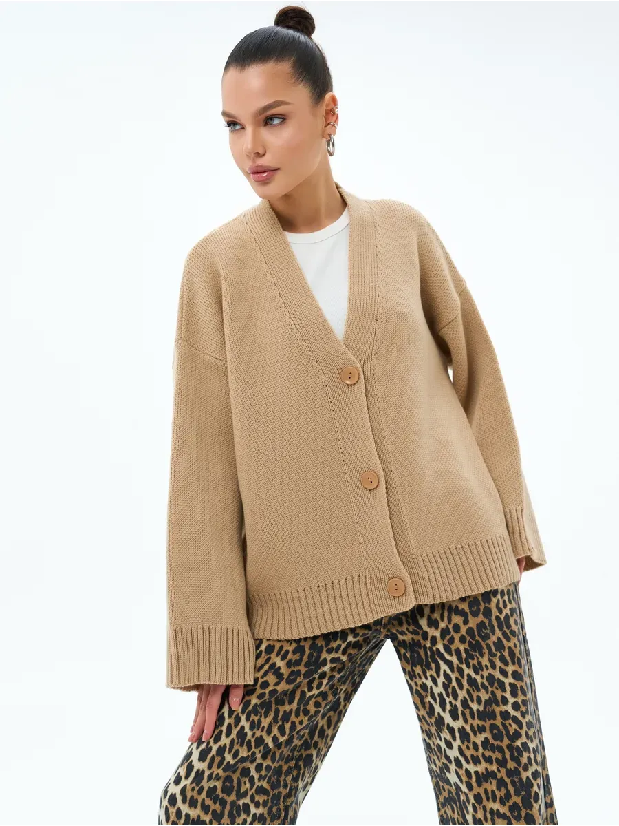 Model wearing a warm Maple Cardigan by Lauven with oversized fit and button closure, styled with leopard print pants.