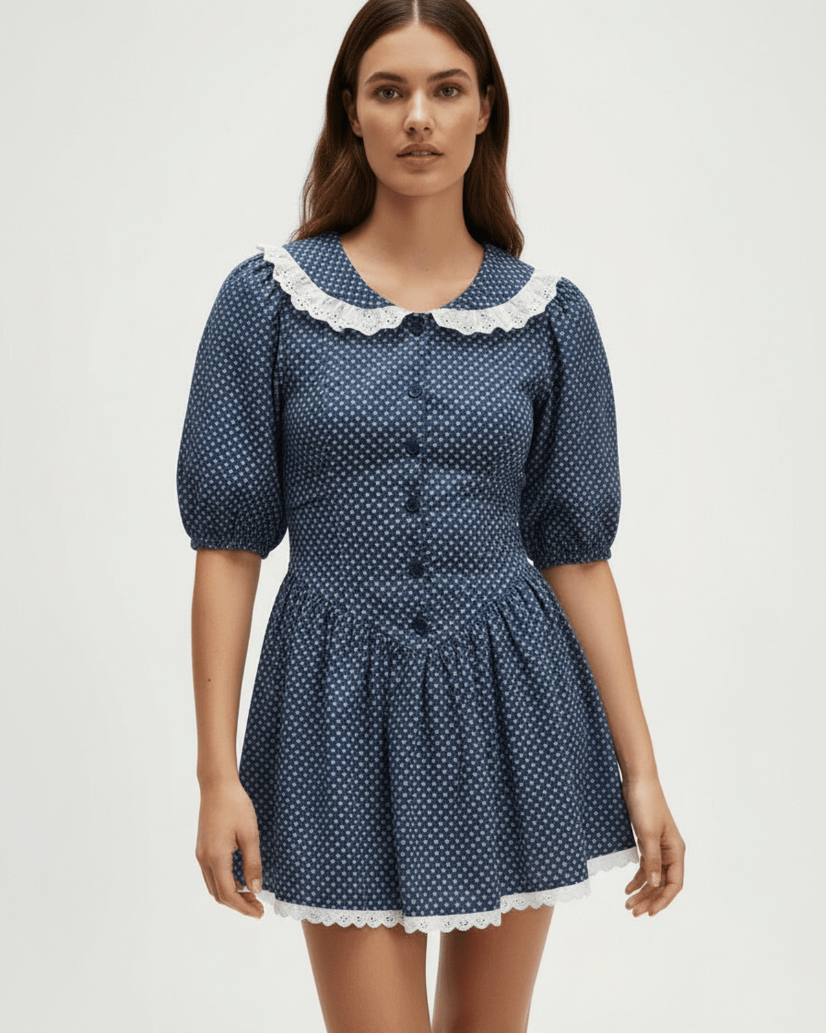 Model wearing Lauven's Marinette Mini Dress with Peter Pan collar and puff sleeves in navy blue polka dots.