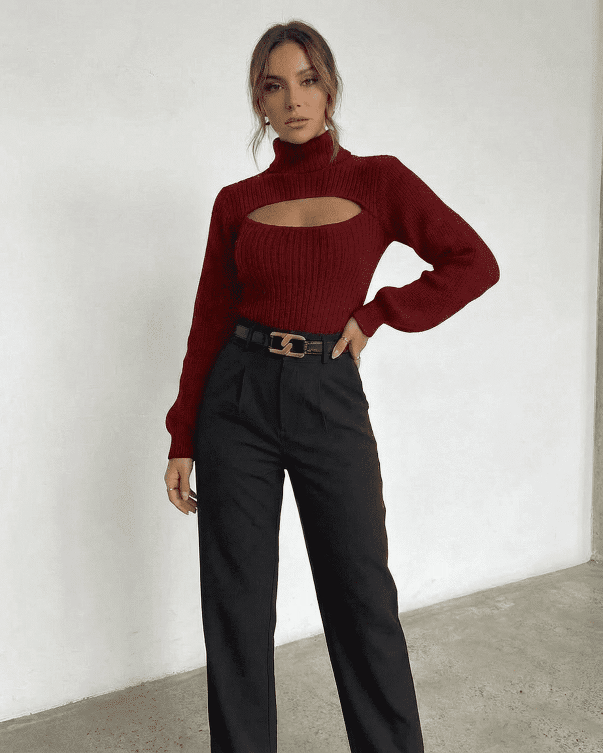 Model wearing the Merlot Sweater by Lauven, featuring a mock neck and cut-out detail, paired with high-waisted trousers.