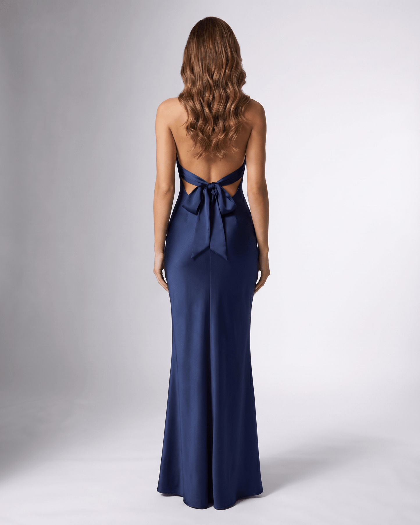Back view of Lauven's Navelle navy blue satin maxi dress featuring a halter neck and bow detail.