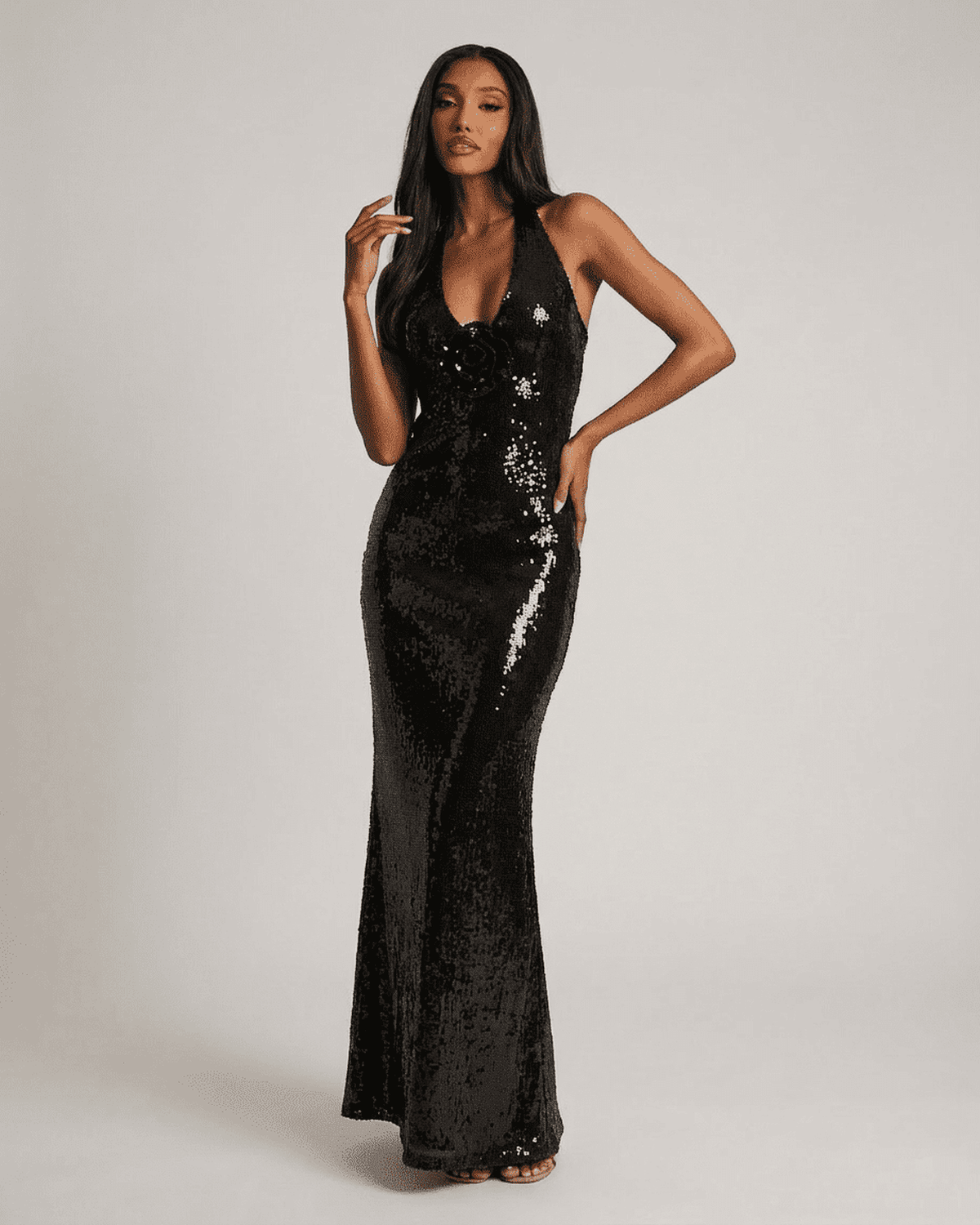 Noiré Maxi Dress by Lauven features a backless V-neck silhouette with floral sequin detail and a shimmering black finish.