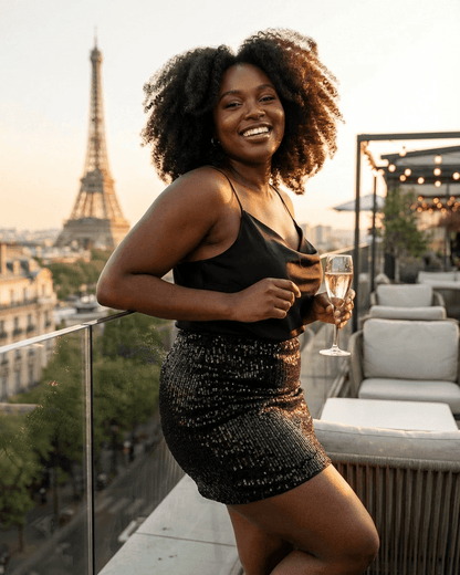 Woman enjoying a sunset in Paris wearing the Noiré Mini Skirt by Lauven with a glass of champagne.