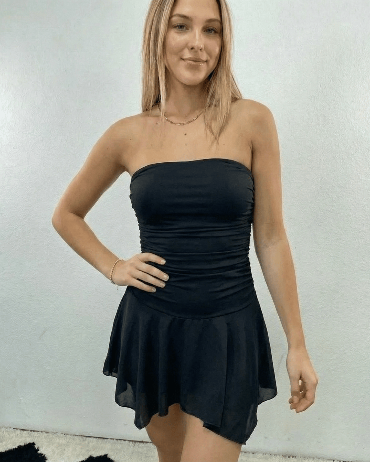 Stylish woman wearing the Nyx Mini Dress by Lauven, a strapless ruched mini dress with a flowy hem.