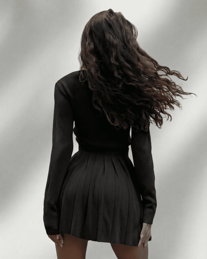 Nyx Two-Piece Set by Lauven featuring a model wearing a knit cardigan and pleated mini skirt from the back.