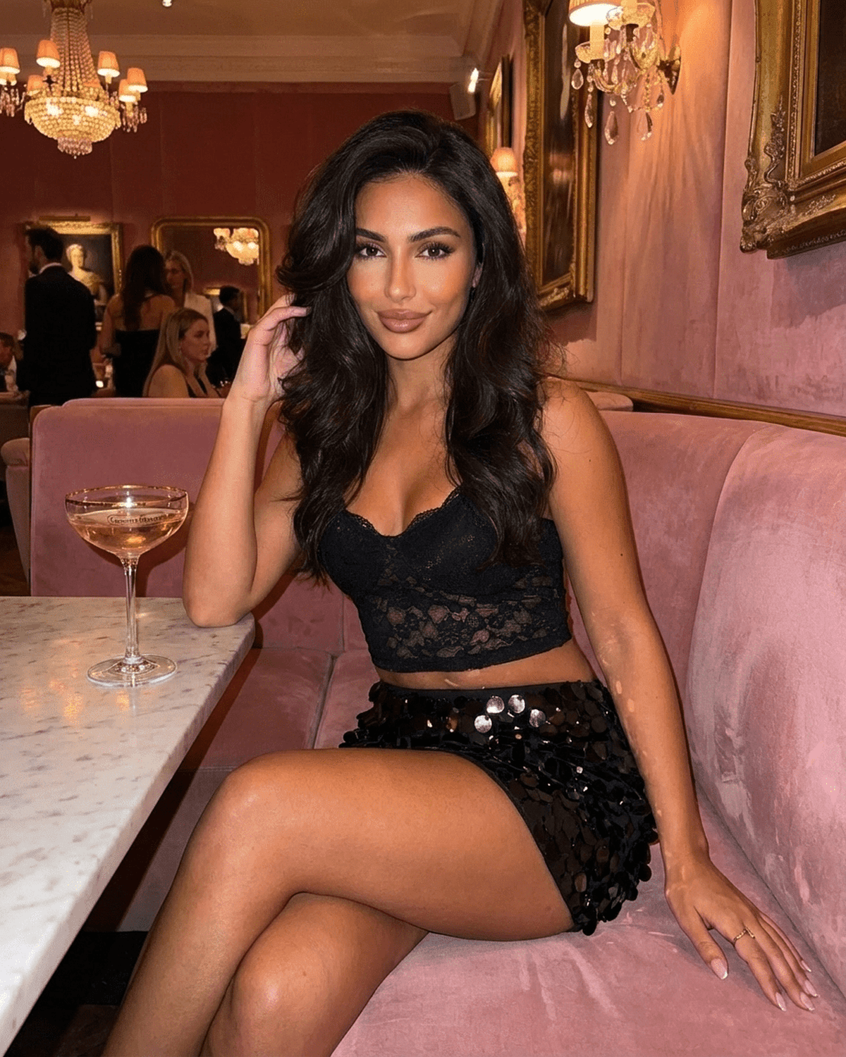 Obsidian Mini Skirt by Lauven worn by a model in a stylish setting with a drink, showcasing black sequin hem bodycon design.