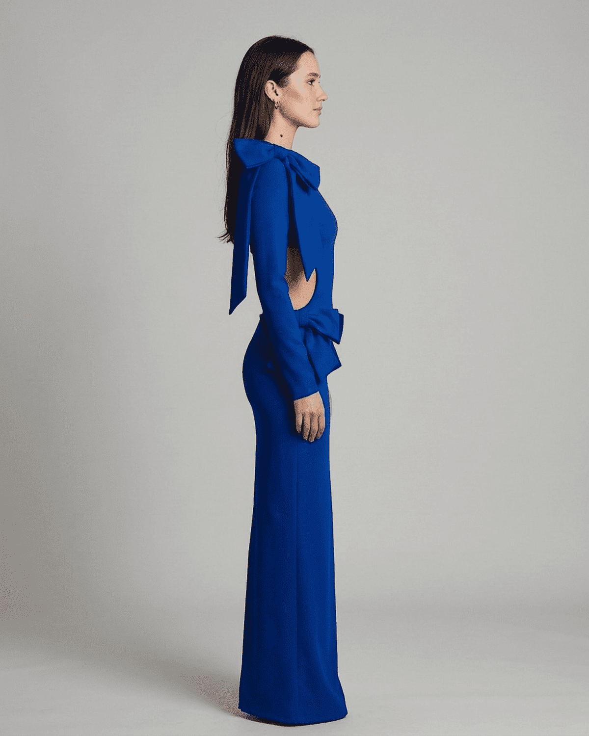 Orion Maxi Dress by Lauven featuring a long sleeve bodycon silhouette with a cut-out waist and sculptural bows in blue.