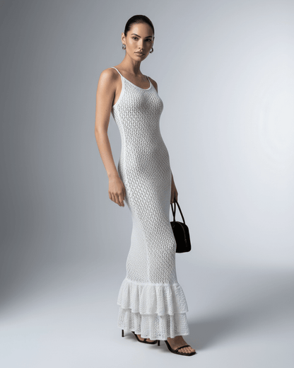 Model wearing Lauven Pearl Maxi Dress, a white hollow out bodycon dress with a ruffled hem.