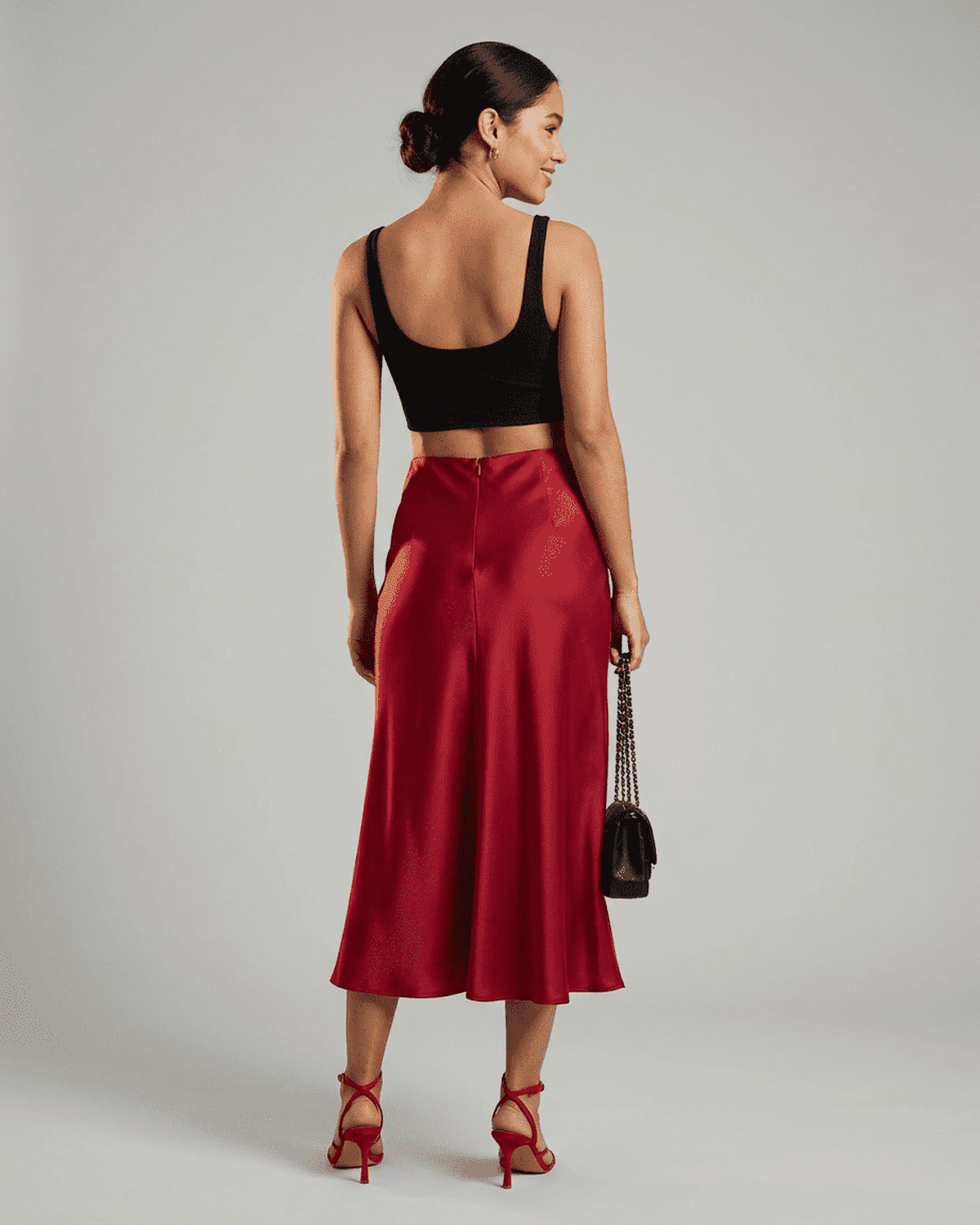 Back view of a model wearing the Rosalia Midi Skirt by Lauven, showcasing its elegant satin mermaid design in rich red.
