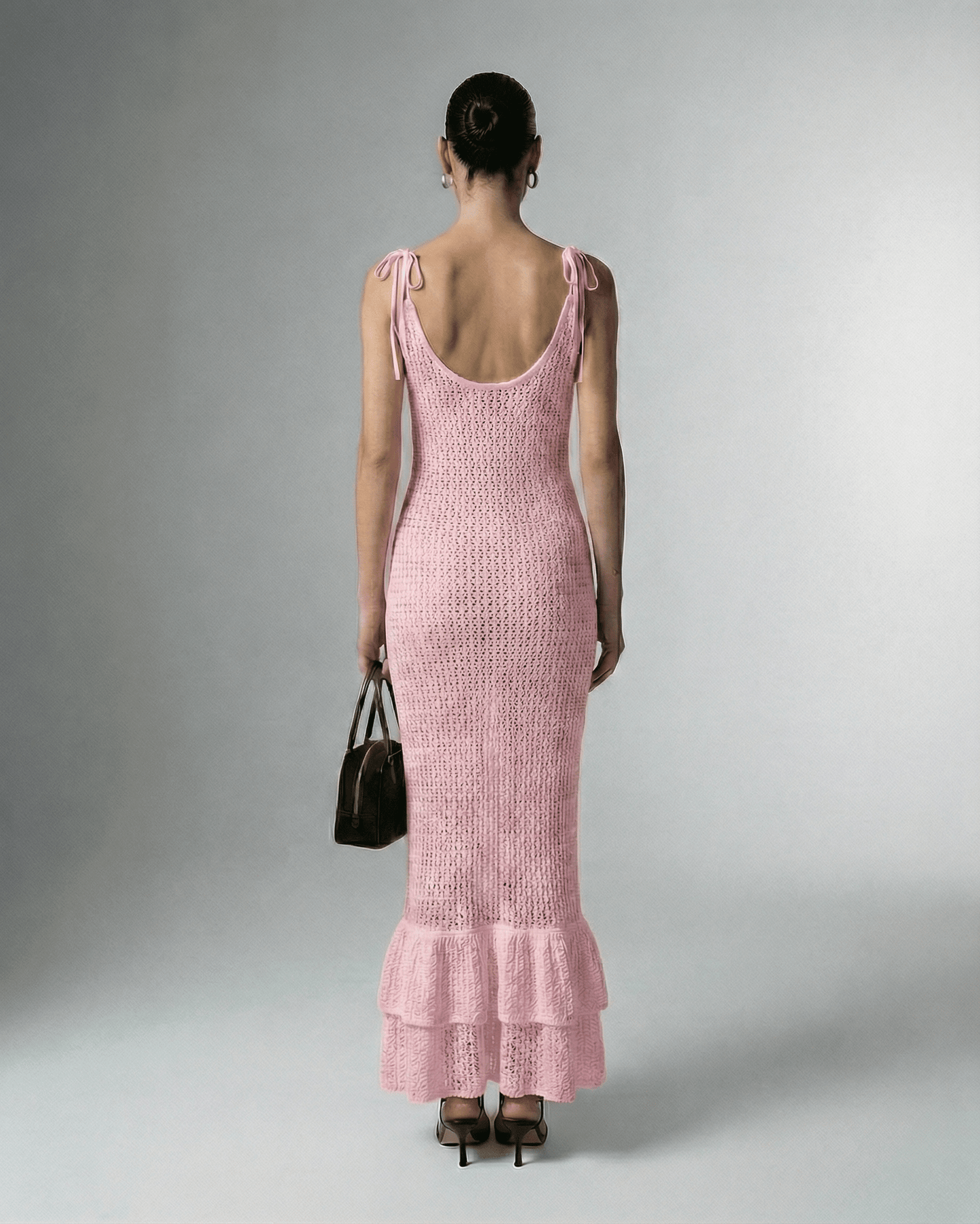 Back view of a model wearing Rosaline Maxi Dress by Lauven, showcasing its stylish pink hollow out knit design.