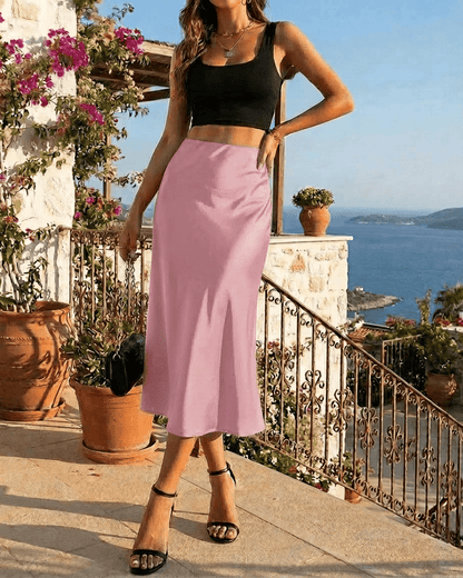 Woman wearing a black crop top and Roselle Midi Skirt by Lauven, posing outdoors with a coastal view.