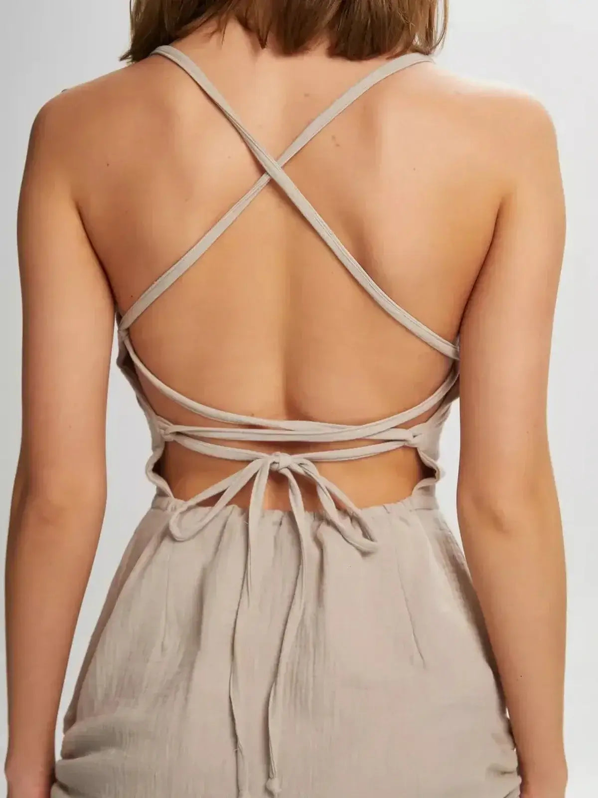 Back view of a model wearing the Lauven Sand Dune mini dress showcasing its lace-up open back and adjustable straps.