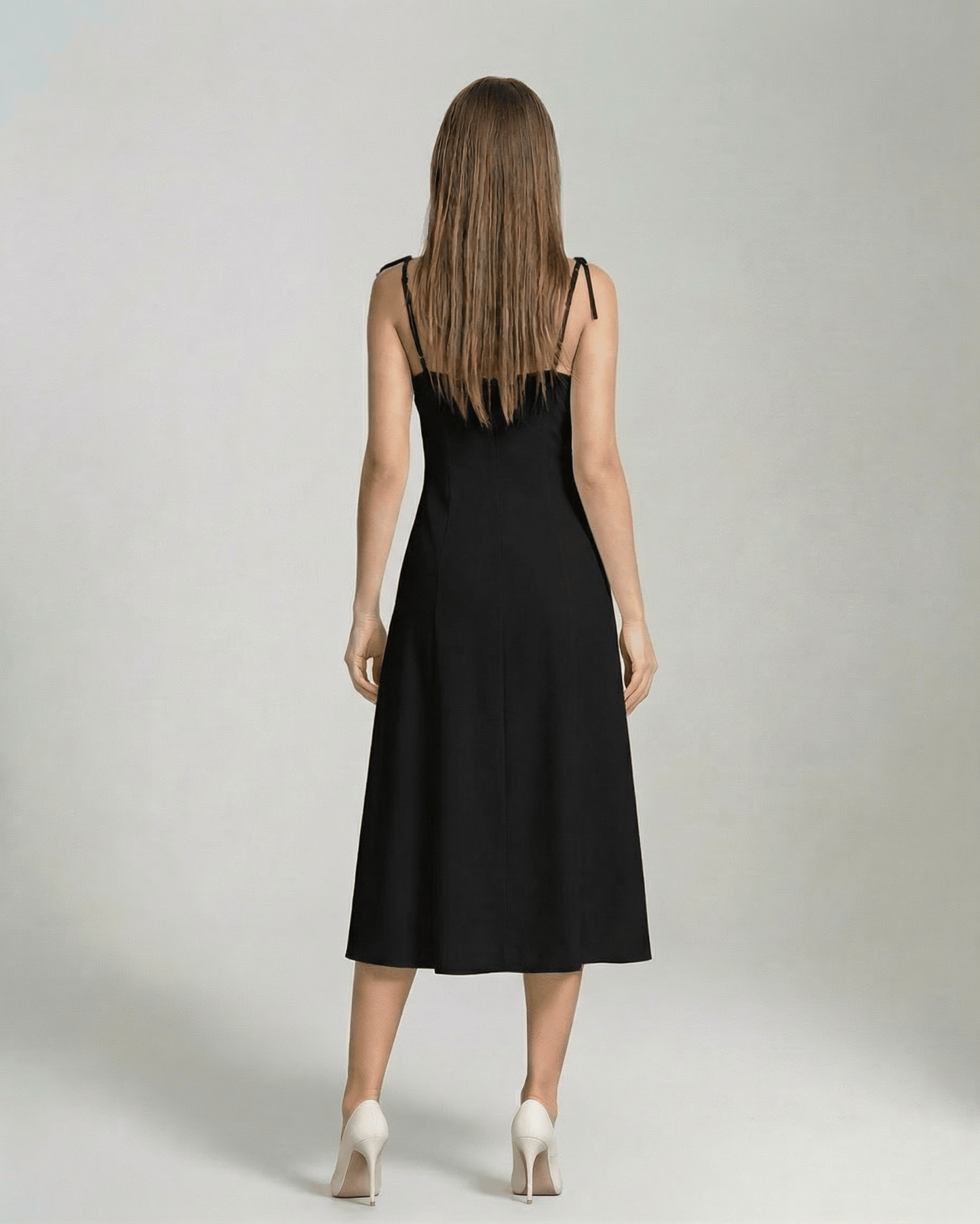 Back view of a woman wearing the Selene Midi Dress by Lauven, an elegant black midi dress with tie straps.