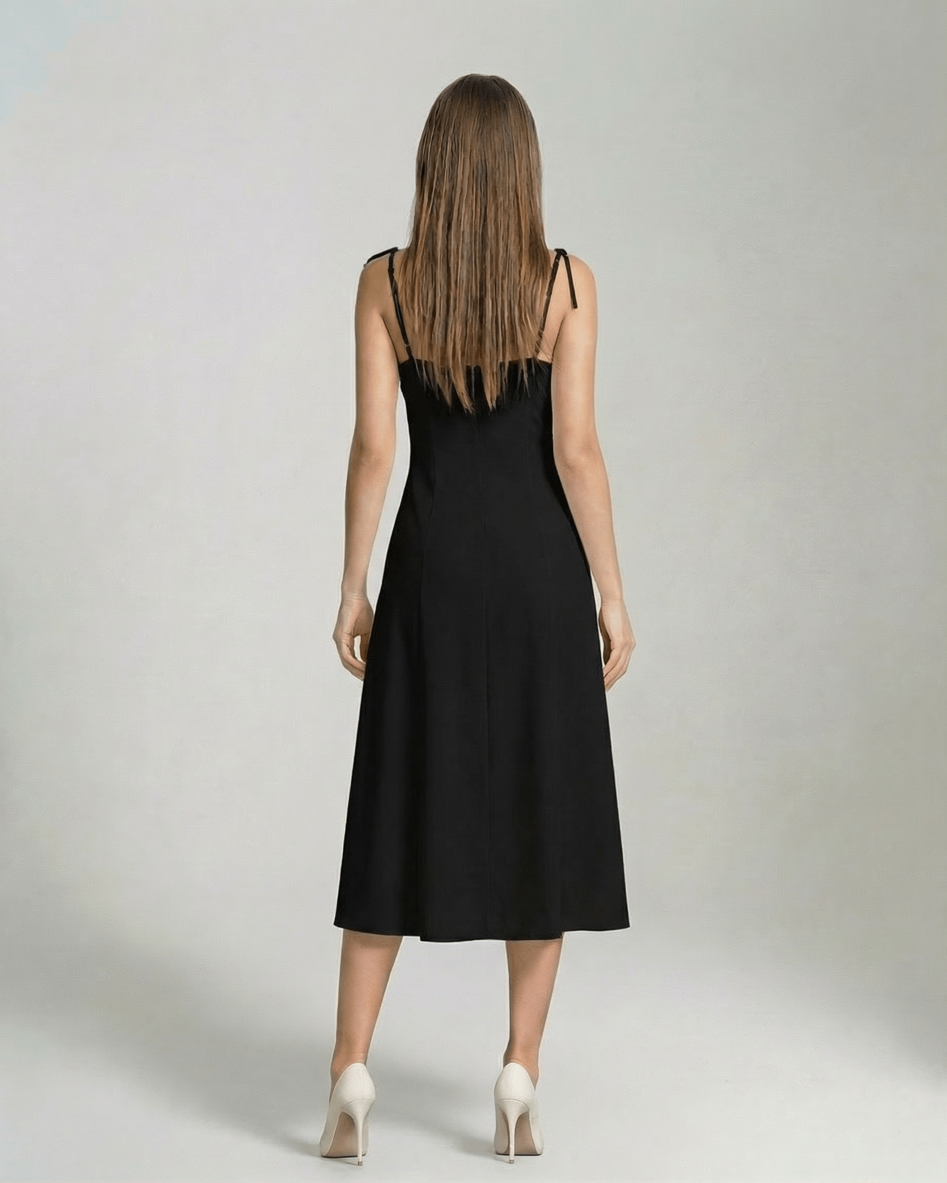 Back view of a woman wearing the Selene Midi Dress by Lauven, an elegant black midi dress with tie straps.