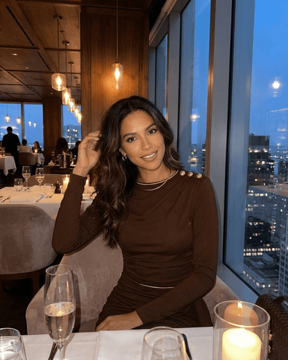 Model wearing Sienna Mini Dress by Lauven in a stylish restaurant setting with city views.