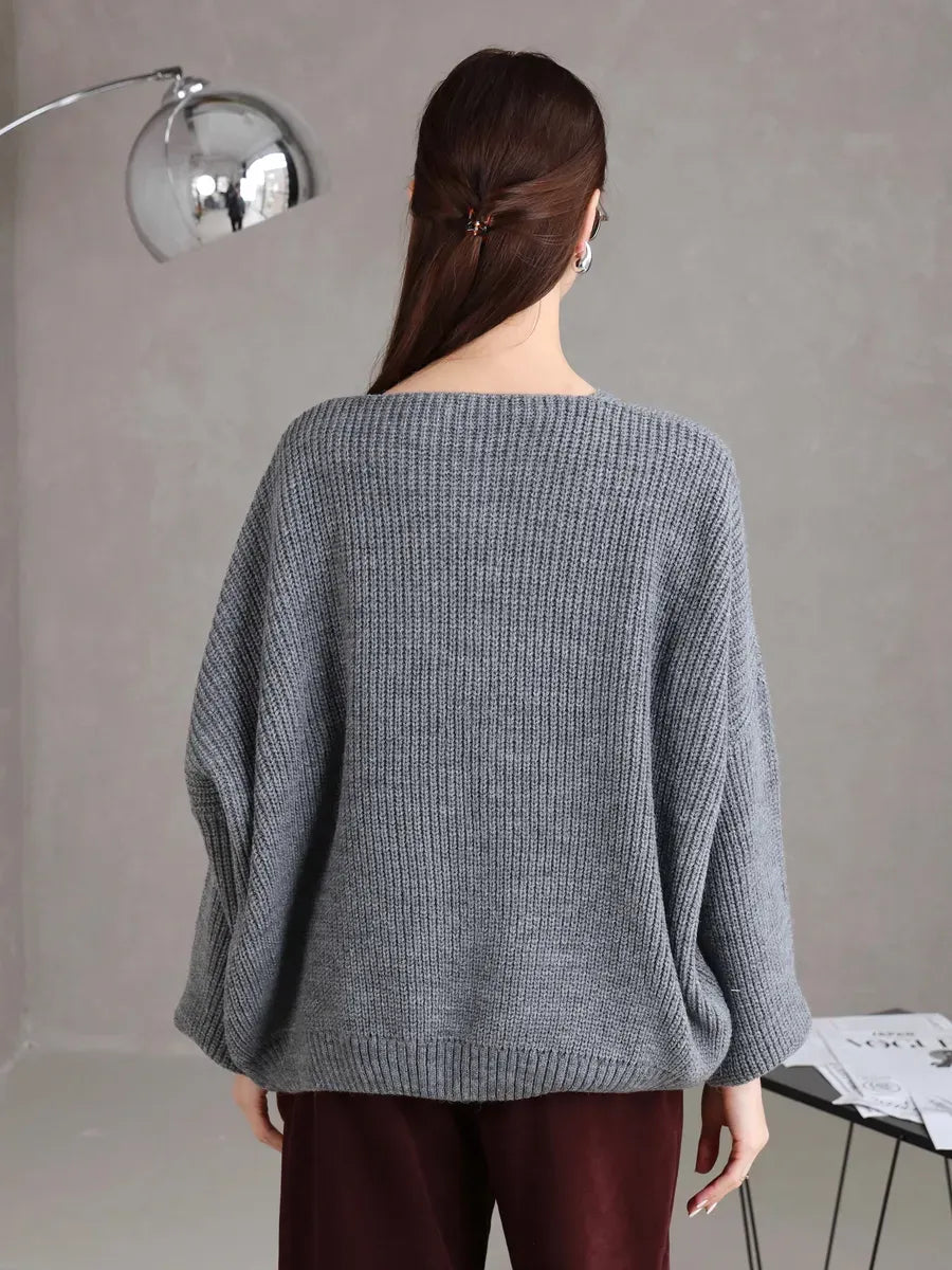 Back view of a woman wearing a cozy Slate Cardigan by Lauven in soft gray, showcasing its oversized fit and tie-front design.
