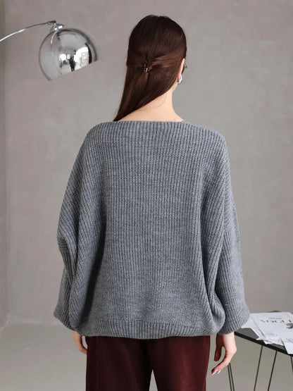 Back view of a woman wearing a cozy Slate Cardigan by Lauven in soft gray, showcasing its oversized fit and tie-front design.