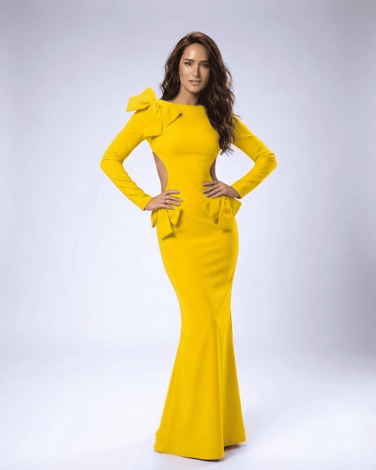 Model showcasing Solara Maxi Dress by Lauven, a stylish yellow long sleeve bodycon dress with cut-out waist and sculptural bows.