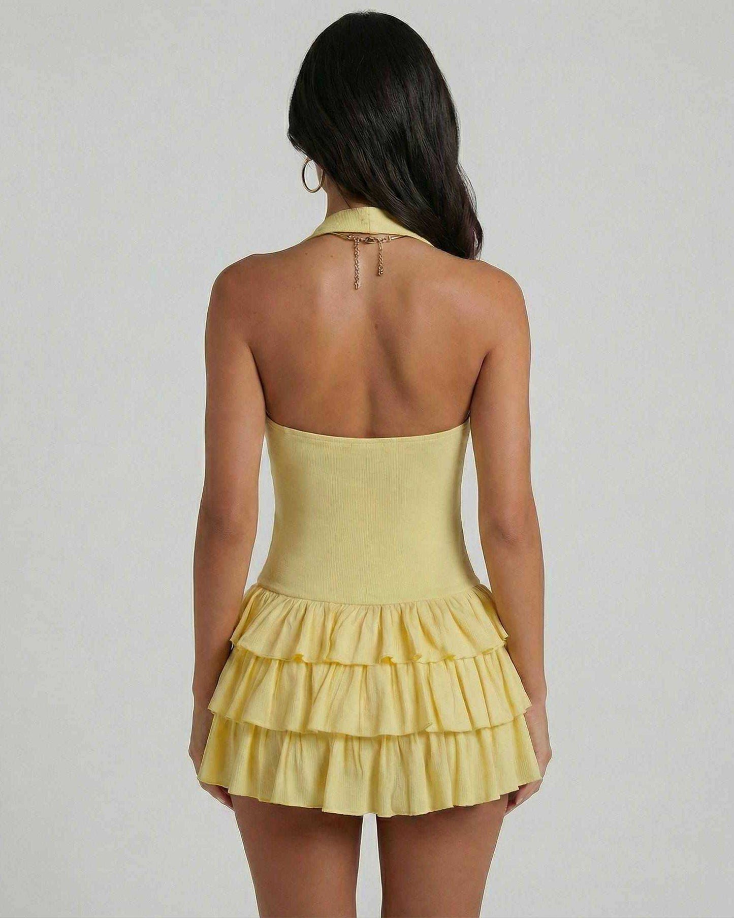 Back view of a woman wearing the Solara Mini Dress by Lauven, featuring a tiered skirt and square neckline in yellow.