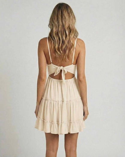Back view of a model wearing the Lauven Soleil Mini Dress with a lace bodice and tiered skirt in beige.