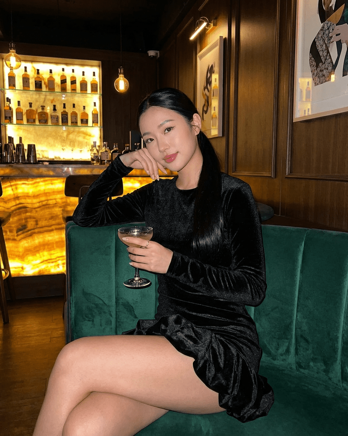 Model wearing Velora Mini dress by Lauven, showcasing the luxe velvet fabric and pleated hem while enjoying a cocktail.