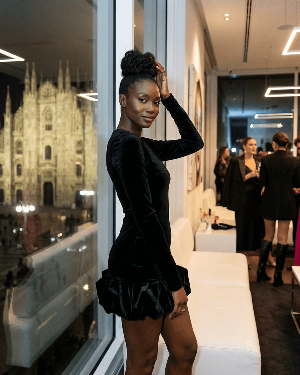 Model showcasing Velora Mini dress by Lauven, featuring luxe black velvet and pleated hem, in a stylish indoor setting.