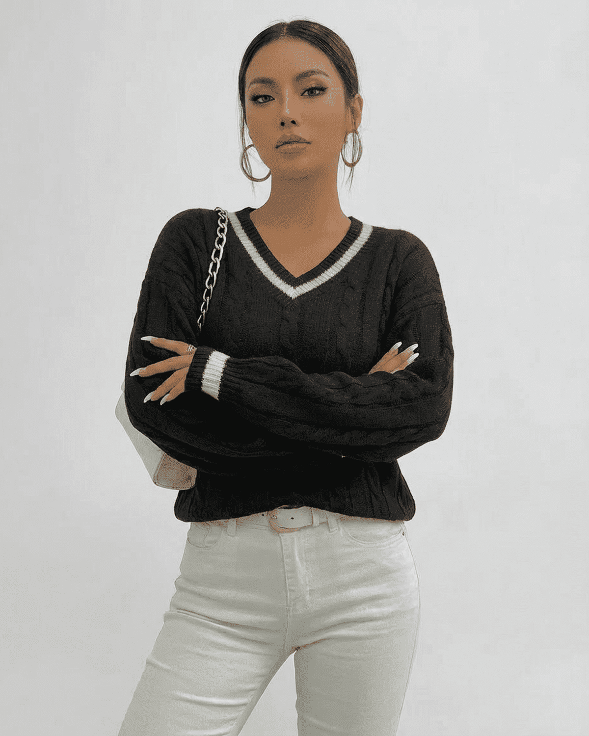 Model wearing LAUVEN Verona Sweater, a cable knit V-neck pullover in black, stylishly posed.