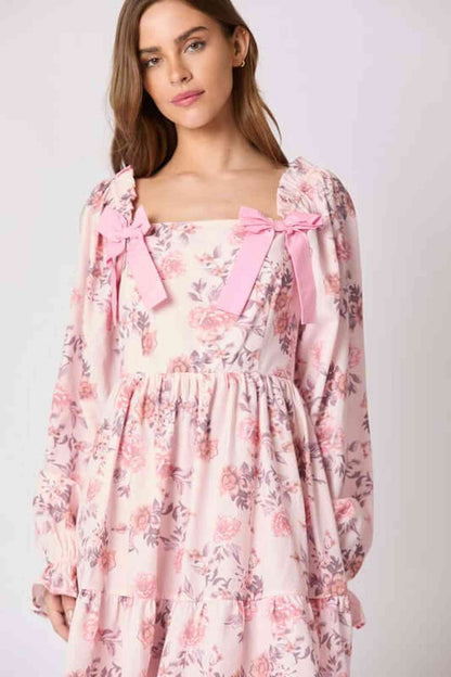 Lila Mini Dress featuring floral print and pink bow accents, perfect for summer weddings and casual outings.