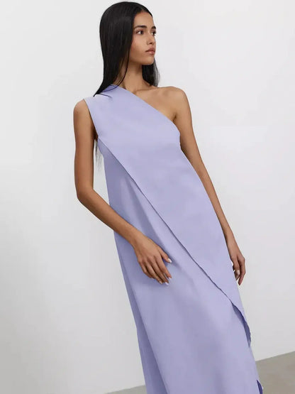 Woman in a lilac one-shoulder maxi dress showcasing sculptural draping and elegant styling.