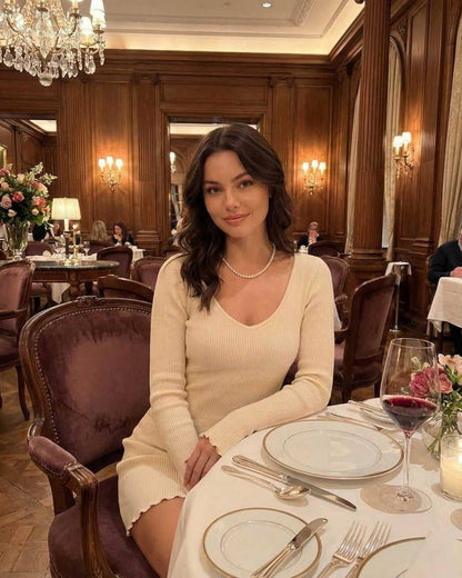 Liora Mini Dress by Lauven in soft cream, adorned with a V-neckline, showcased in an elegant dining setting.