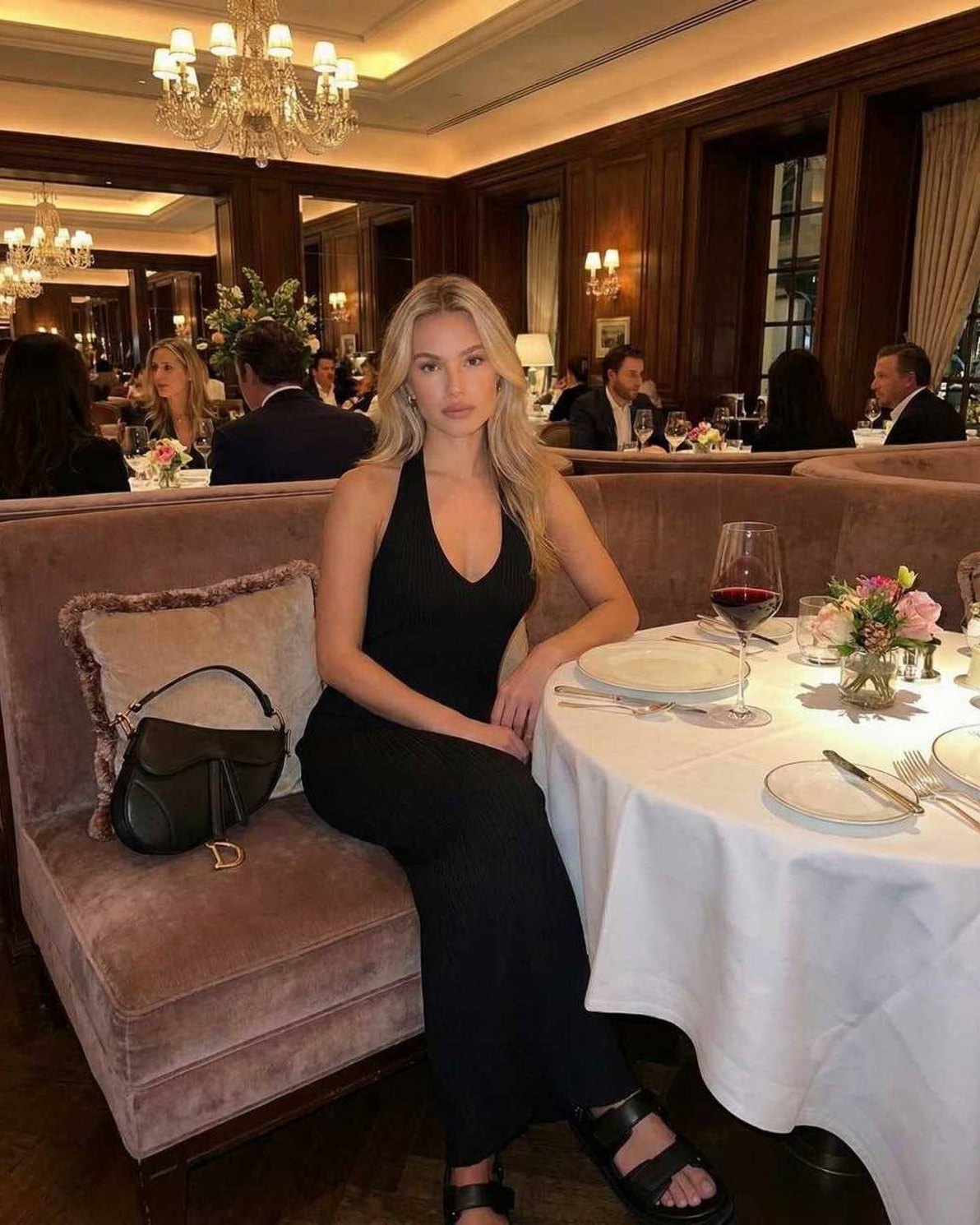 Luna Maxi Dress by Lauven worn by a woman in a chic restaurant setting, showcasing its sleek black design.